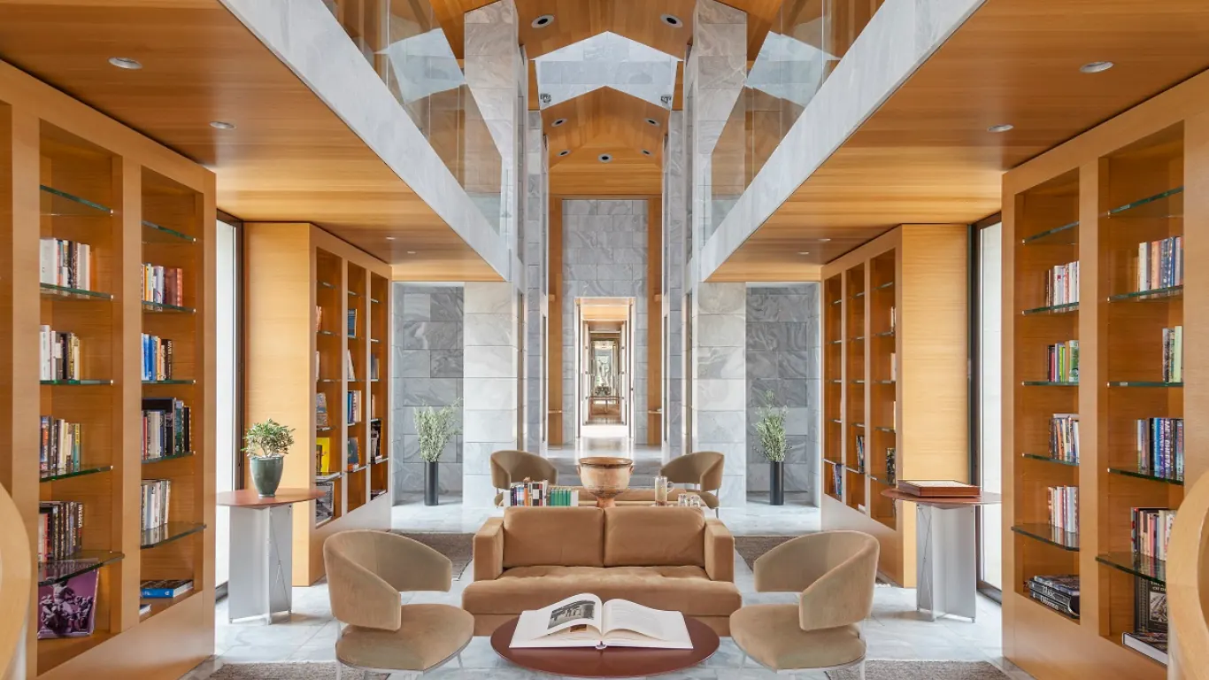 Symmetrical library lounge with timber bookshelves and an open book on a low table