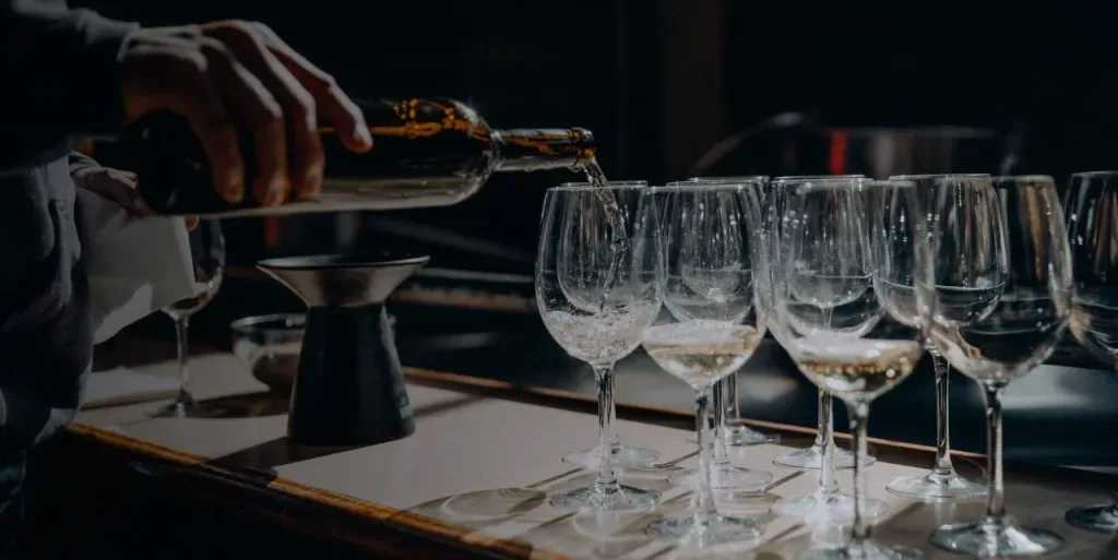 A sommelier pouring wine into a row of glasses